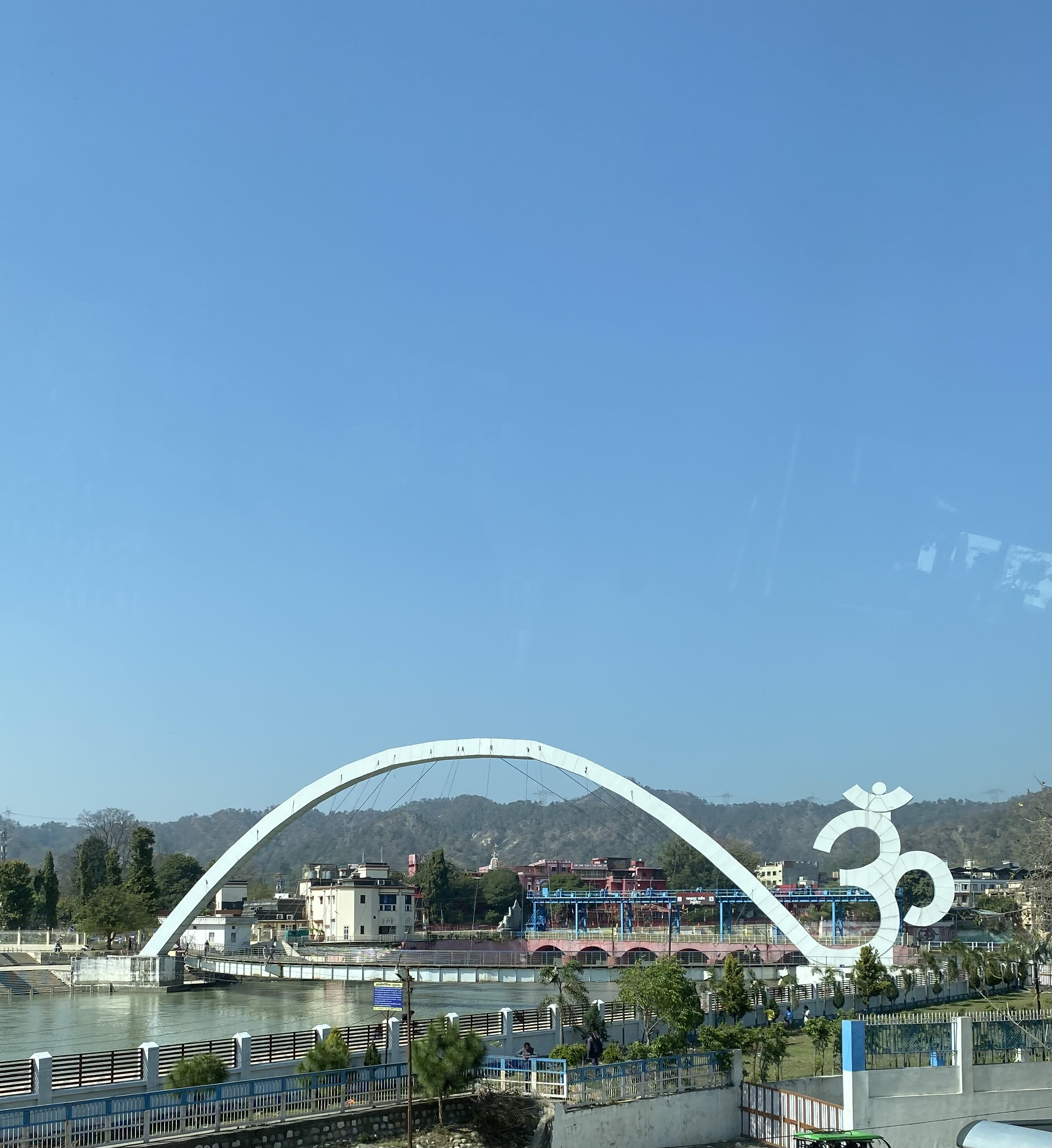 Brücke über einen Fluss mit großer Om-Skulptur – Yogareise Nordindien