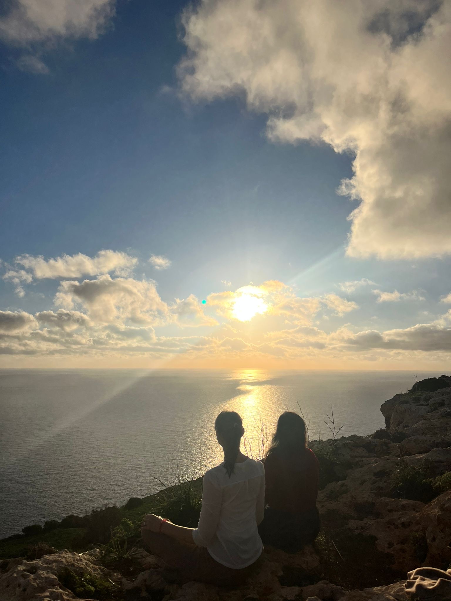 Zwei Personen meditieren bei Sonnenuntergang am Meer