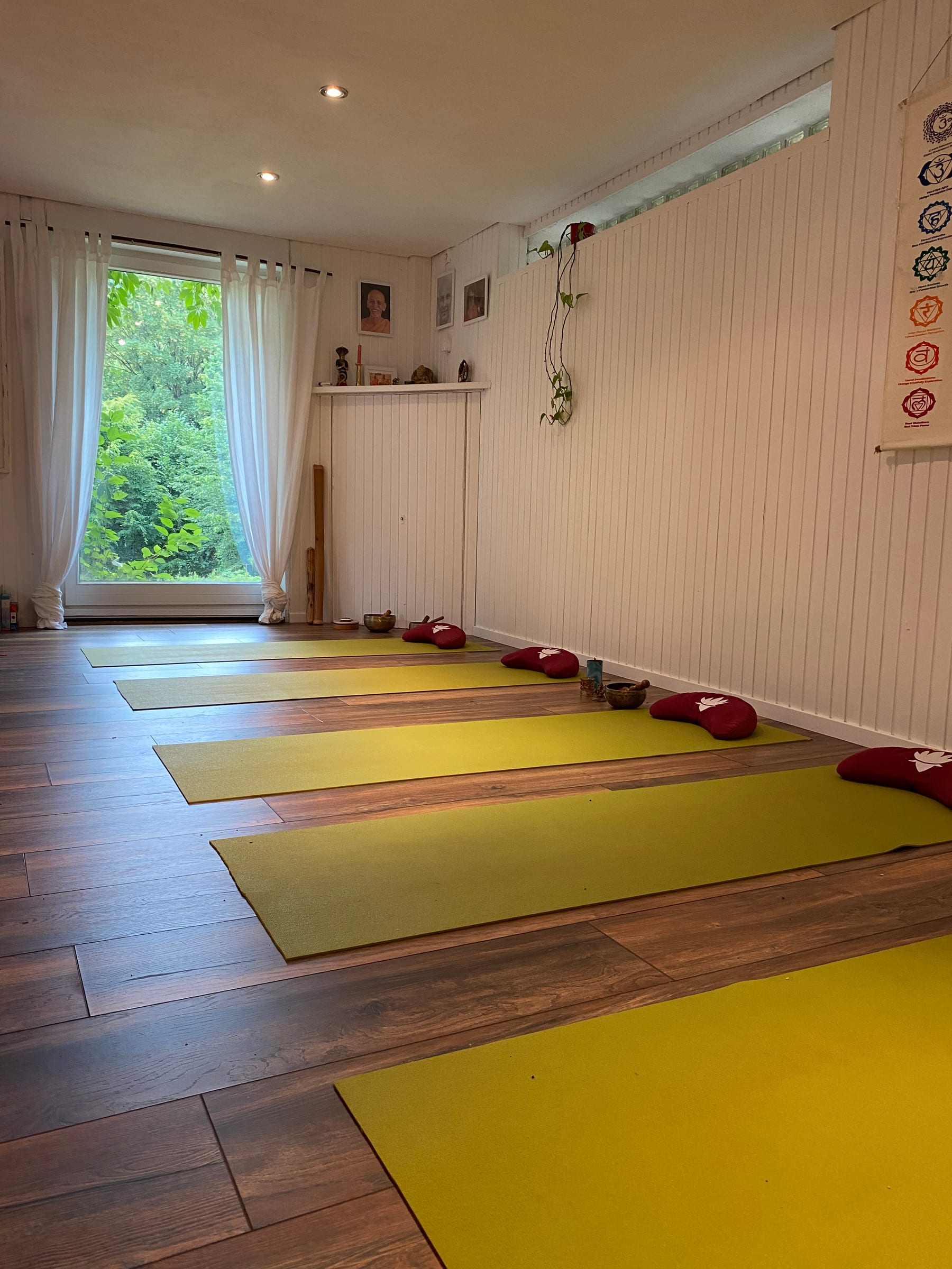 Yogaraum in Herdecke mit ausgelegten Yogamatten, Meditationskissen und Blick ins Grüne